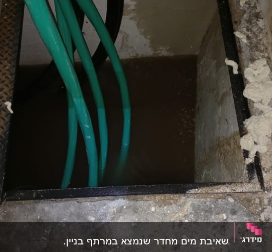 צינורות ירוקים בתוך בור עם מים כהים